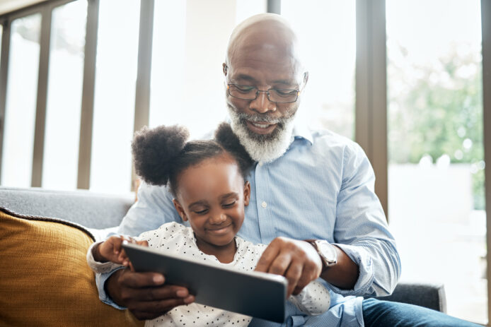 Older male shows a family member something on his tablet.