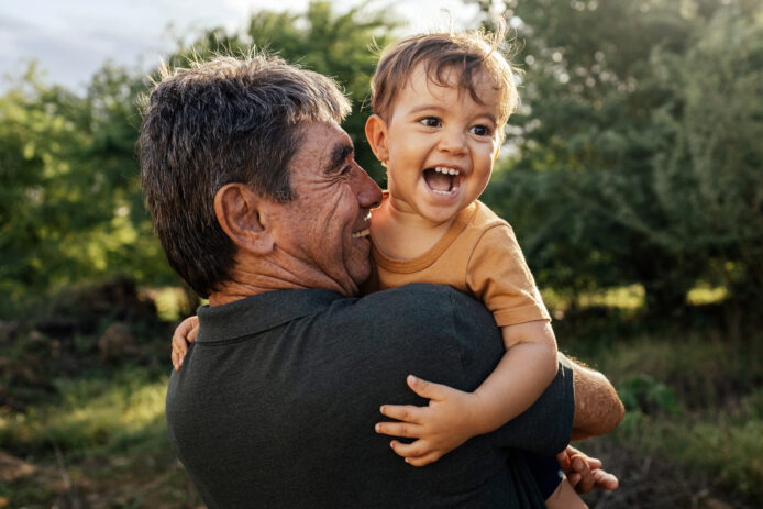 Older male holds up a happy child